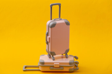Travel still life, vacation or tourism concept. Two mini travel luggage suitcase on yellow background