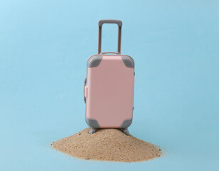 Mini travel luggage suitcase on a sand island. Studio conceptual shot. Travel, beach vacation concept