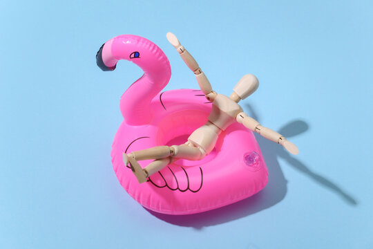 Puppet mannequin with inflatable flamingo on blue bright background. Beach vacation concept. Summer rest. Minimalism