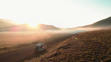 Aerial view, camper van parked in the meadow in the morning, lights of dawn with fog in the landscape. 4k
