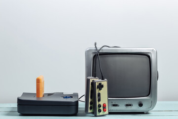 Old tv receiver with retro game console, joysticks on a white wall background. Retro gaming. 80s