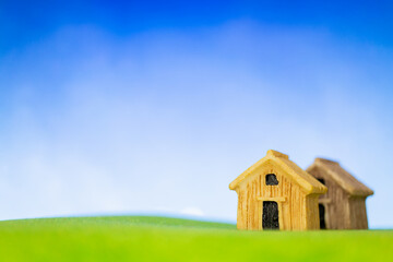 Wooden house model on green grass. Eco-friendly house concept.