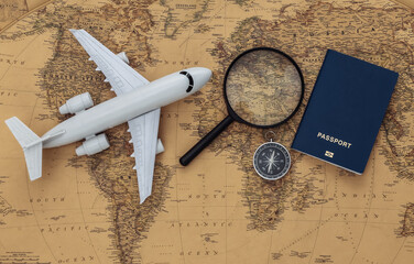 Magnifying glass and air plane, compass, passport on old map. Travel, adventure concept