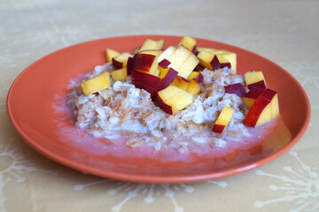 oatmeal porridge with chopped fresh peach in a plate, vegetarian breakfast