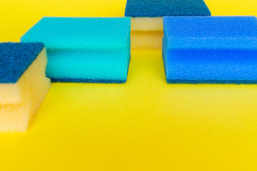 Dish washing sponges of different colors are on a yellow background. High quality photo
