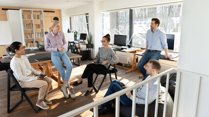 Obraz premium Multiracial businesspeople gather in office brainstorm discuss business project or idea together, diverse colleagues coworkers talk engaged in teambuilding activity at meeting or briefing in boardroom