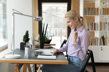 Overjoyed young Caucasian female employee look at laptop screen feel euphoric winning online...