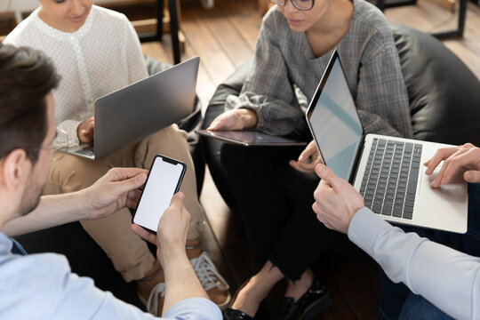Top view close up of diverse employees sit in circle brainstorm discuss business ideas using gadgets, colleagues work on modern devices, cooperate at meeting briefing in office, technology concept