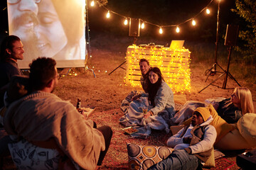 Group of young restful intercultural men and women relaxing on rug and pillows