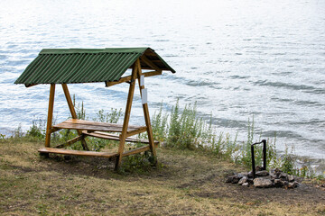 arbor on the shore and a place for a fire on the background of nature.