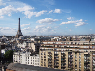 
Paris skyline with the Eiffel Tower shining during the day when clouds seem to float comfortably in the clear sky.