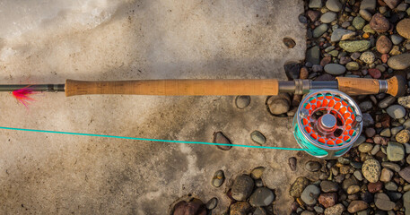 Salmon spey fly rod and reel resting on gravel and snow