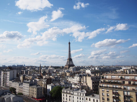 
Paris skyline with the Eiffel Tower shining during the day when clouds seem to float comfortably in the blue clear sky.