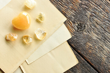 A top view image of yellow calcite heart shaped crystal and old vintage writing paper. 