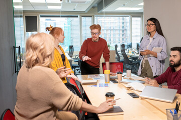 Fototapeta premium Young confident broker debating with one of colleagues explaining her viewpoint