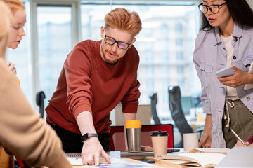 Confident young businessman pointing at financial paper during discussion