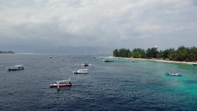 Summer time in the Gili Travangan Island with cruise boats. The drone shot of the island nearby.