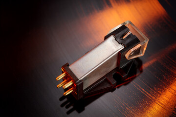 Magnetic phonograph cartridge on vinyl record groove.