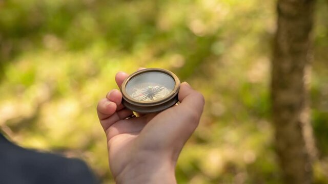 Traveler hand holds a compass in forest