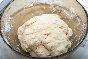 Thick dough is manually mixed in a transparent bowl.
