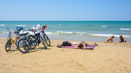 Fototapeta na wymiar On the sandy seashore, a family arriving on bicycles rests
