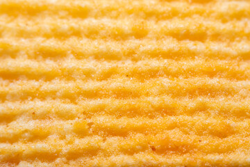Background with a close-up of the surface of potato chips with a strong increase in soft focus. Corrugated surface with crumbs and drops of oil.