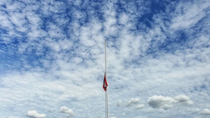 The national flag was dropped in half. The background is bright, with beautiful streaks and clouds.