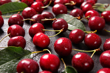 Sweet cherry on a black background with leaves and drops of water.