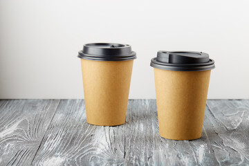 Two take away paper coffee cups on grey wooden background