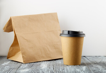 Take away paper coffee cup with lunch bag on grey wooden background