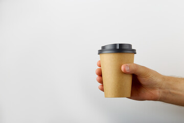 Male hand holding a take away coffee paper cup on white background