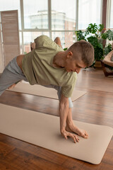 Young active man in sportswear standing on mat with one arm behind back