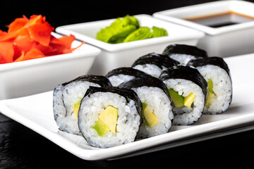 Vegetarian Rolls with avocado on a white plate on a dark background. Sushi menu. Japanese food.
