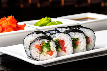 Vegetarian Rolls with cucumber and tomato on a white plate on a dark background. Sushi menu. Japanese food.