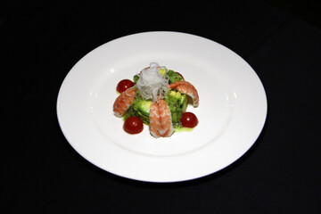  Salad of avocado, kiwi and tiger shrimp on a white plate