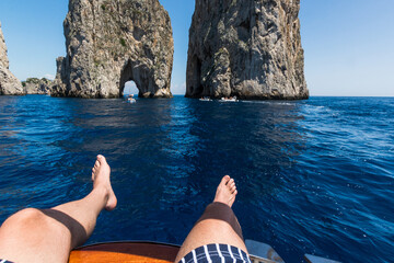 Italian man exploring Capri by sitting on the top of his boat, view of the Faraglioni.