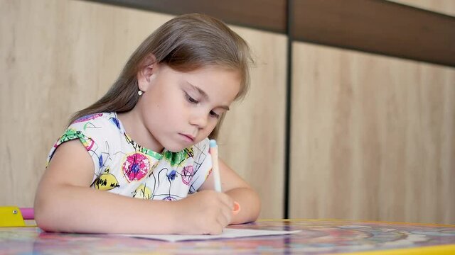 Happy little girl or cute primary child school child painting or writening on paper. Children elementary education concept.
