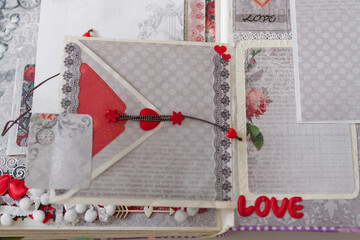 Soft focused close up shot of scrapbooking photo album page with paper decorative elements, flowers, hearts, ribbons, beads. Leisure and hobby concept.