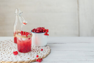 Fresh red currant cocktail in glass jar. Summer pink cocktail with red currant and ice cubes on white wooden background mock up with copy space for text.