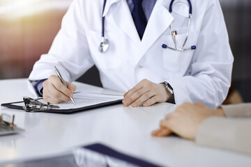 Unknown male doctor and patient woman discussing something while sittingin a darkened clinic and...