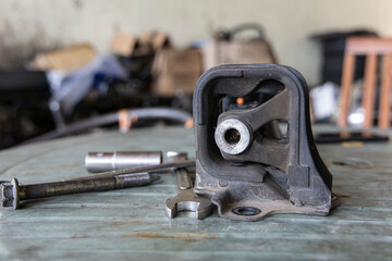 Old rubber engine mount with tools on the table background.