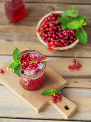Glass of red currant cocktail or mocktail, refreshing summer drink with crushed ice and sparkling water on a wooden background.