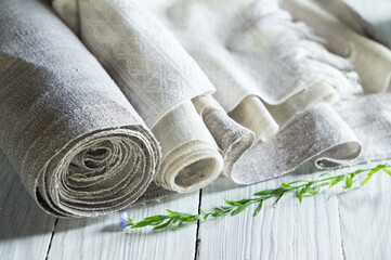 Fototapeta na wymiar Old homespun and modern factory linen fabrics in rolls and blooming flax