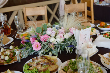 Beautiful floral arrangement of rose flowers and greenery on wedding table in restaurant, copy space. Luxury wedding decorations. Table setting
