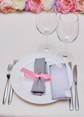Table set with blank guest card, plate with white napkin and cutlery on table, copy space. Place setting at wedding reception. Table served for wedding banquet in restaurant