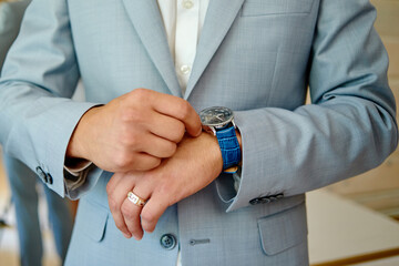 Businessman looking at watches on his hand indoors, copy space. Man in suit checking time from luxury wristwatches. Watch on hand. Groom wedding preparation