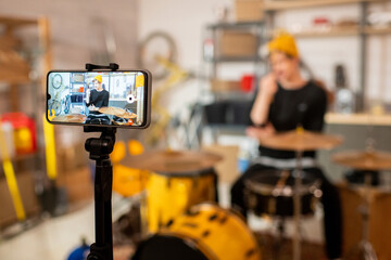 Young contemporary musician in front of drumset on smartphone screen