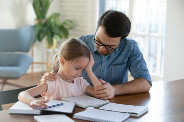 Caring father helping upset little daughter with school homework, sad pretty girl having problem...