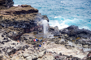 People standing around Nakalele Blowhole Geysir at rocky coast line or shore on North Maui Island...