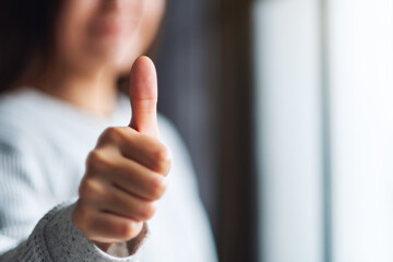 Closeup image of a woman making and showing thumbs up hand sign